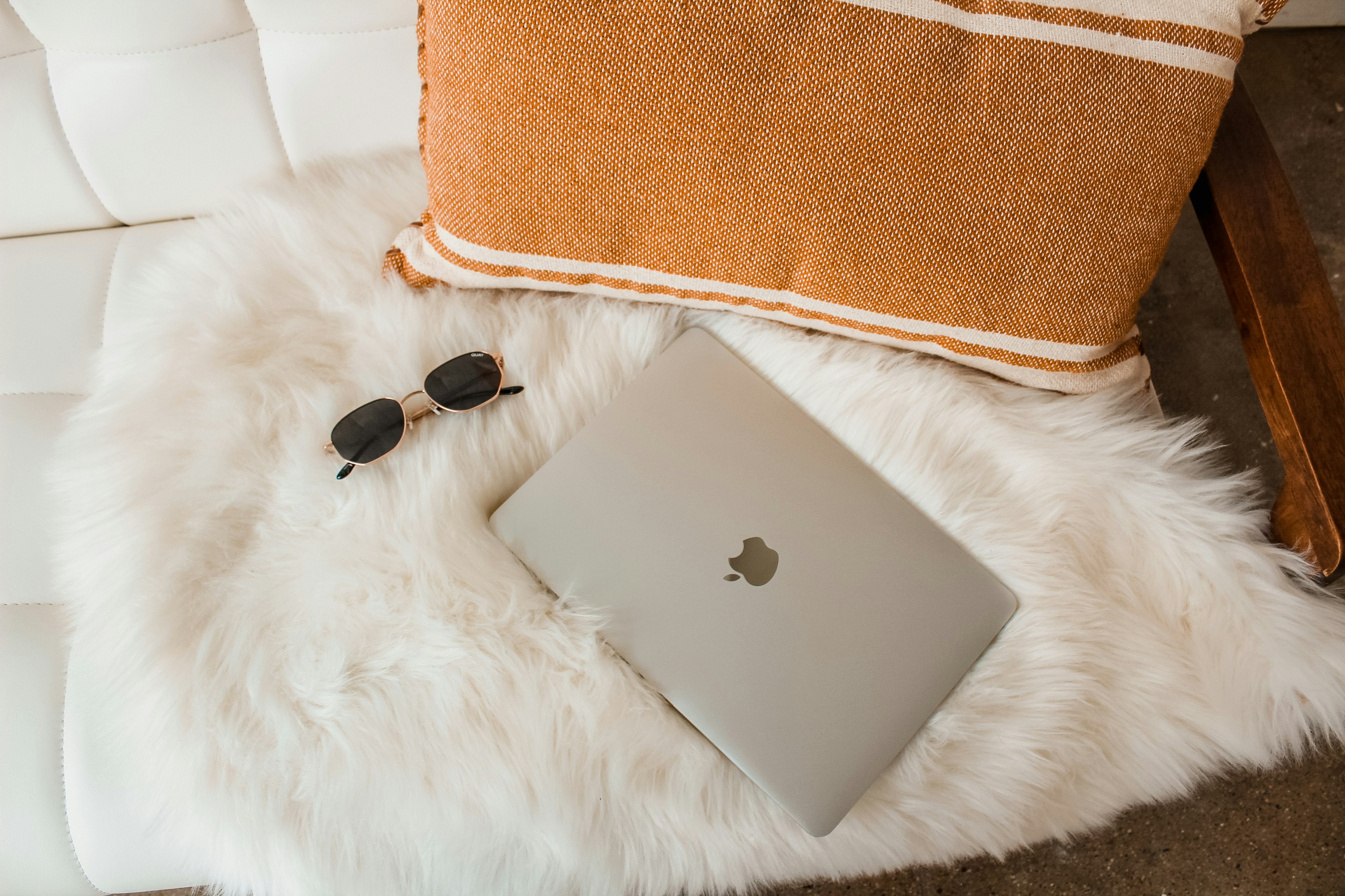 silver macbook on white fur textile